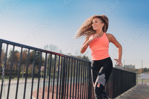 Young attractive woman enjoying outdoor physical exercise in the city running