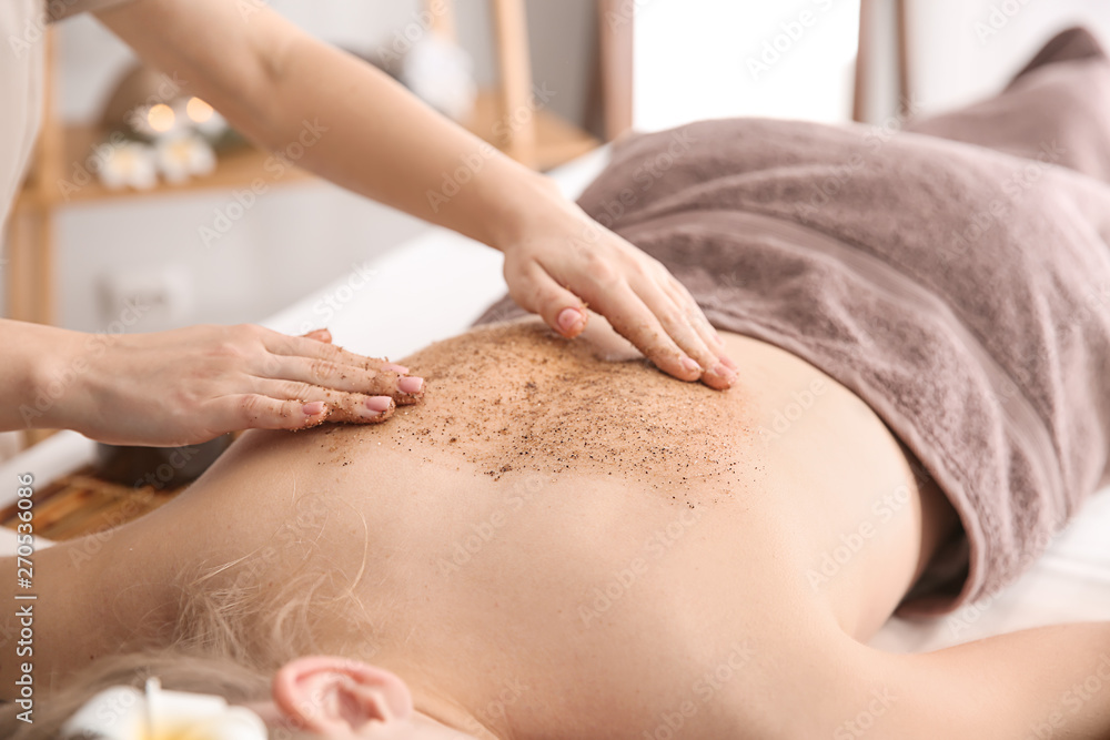 Young woman undergoing treatment with body scrub in spa salon Young woman undergoing treatment with body scrub in spa salon