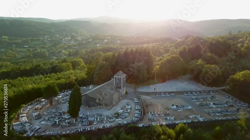 Drone shot of a church and a cemetery surrounded by a forest. Sunset photo