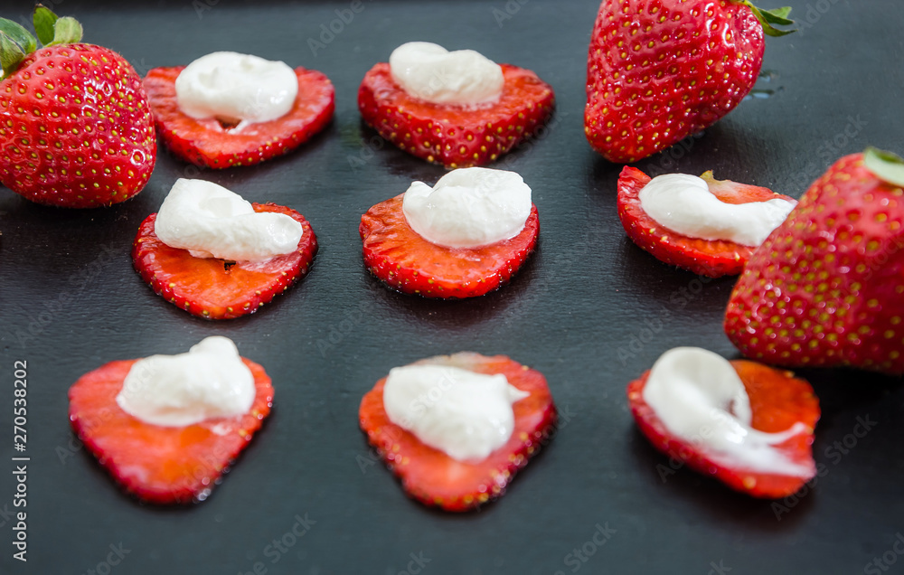 Delicious strawberries with cream on a black background. Background with strawberries. Delicious strawberries with cream on a black background. Background with strawberries.