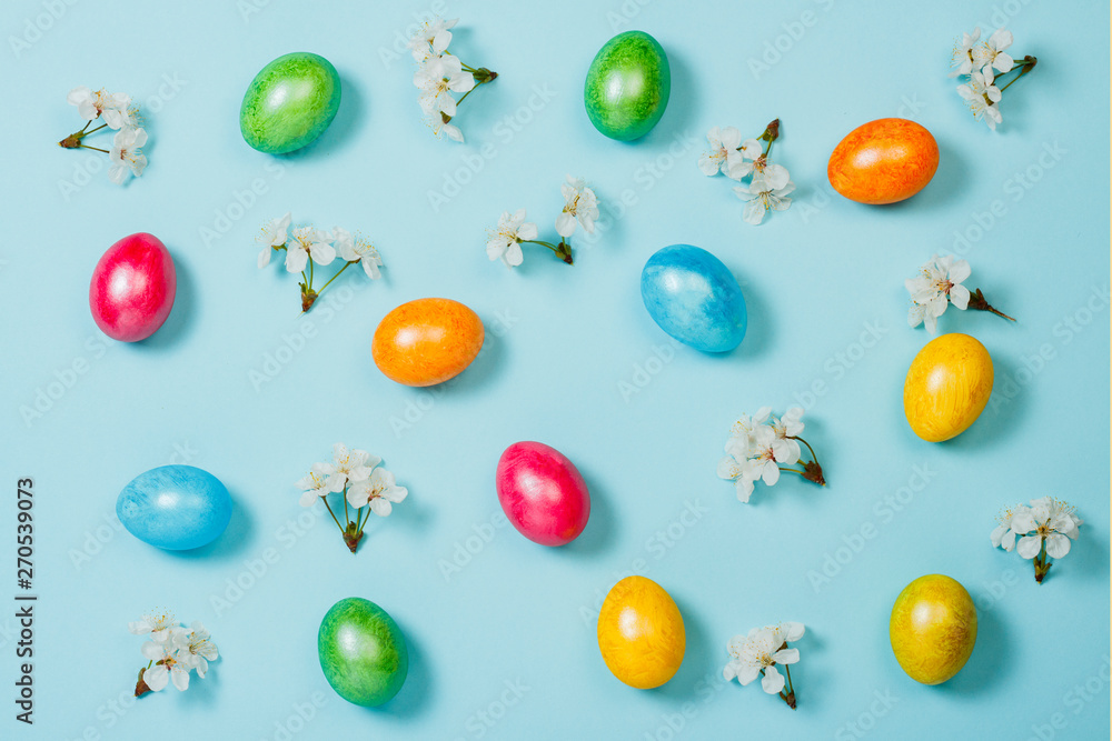 Easter eggs and spring flowers on a blue background. Concept of celebrating Easter. Flat lay, top view