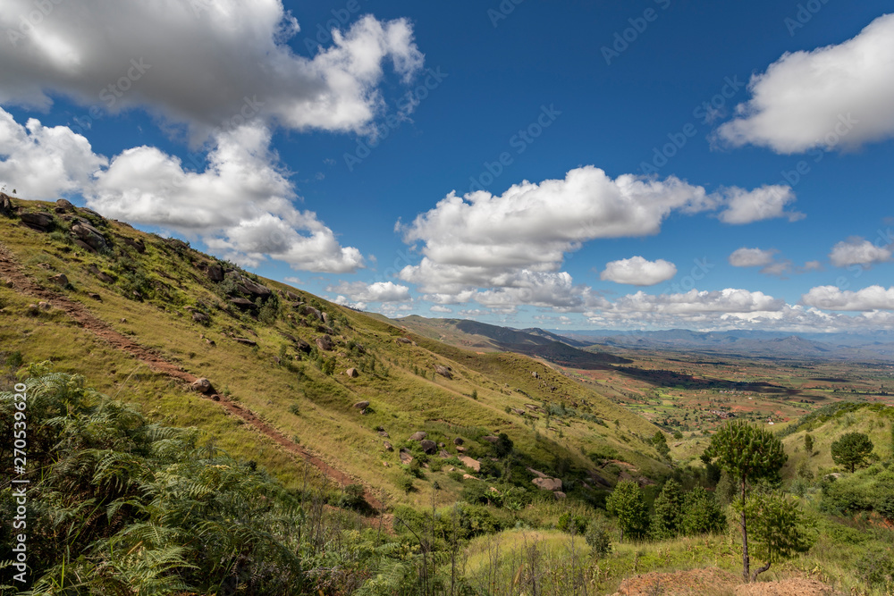 Rural mountain landscape in Central Madagascar. Deforestation hills, a valley and mountains on the background with clouds above