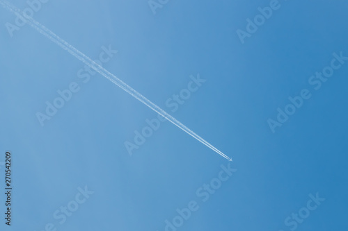 Trail of jet plane on clear blue sky.