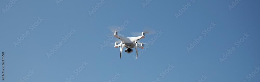 Drone on blue sky background. Remote control quadrocopter with camera for photography. Flying robot.