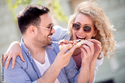 Couple eating pizza snack outdoors