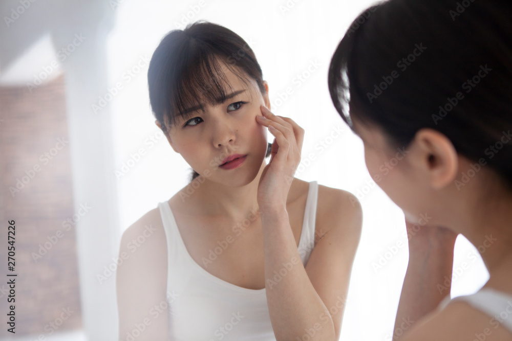 険しい表情で肌を触る女性