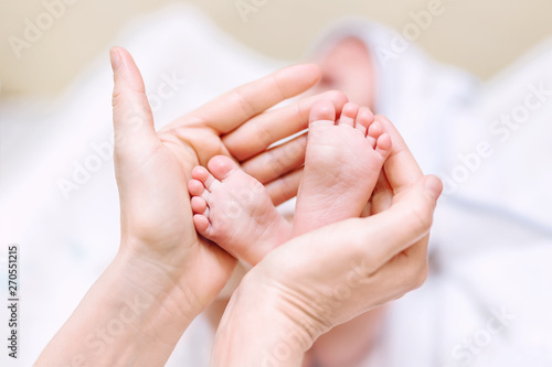 Mother holding newborn baby feet in hands. Mom taking care about infant child after taking bath. Parents childcare. Children healthcare and happy family © Kirill Gorlov