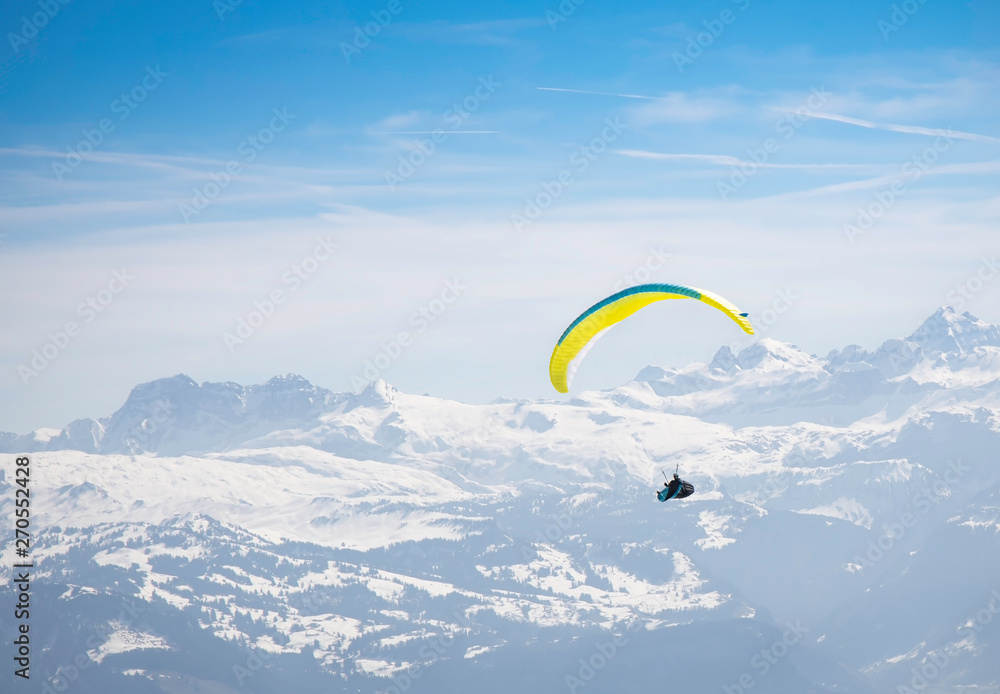 Happy time of young man Paragliding in the sky. flying over the snow mountain with blue sky Happy time of young man Paragliding in the sky. flying over the snow mountain with blue sky