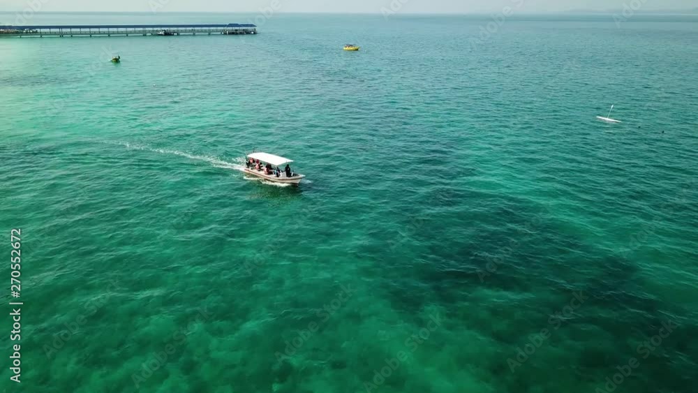 Drone view of a boat sailing across the blue clear waters Drone view of a boat sailing across the blue clear waters