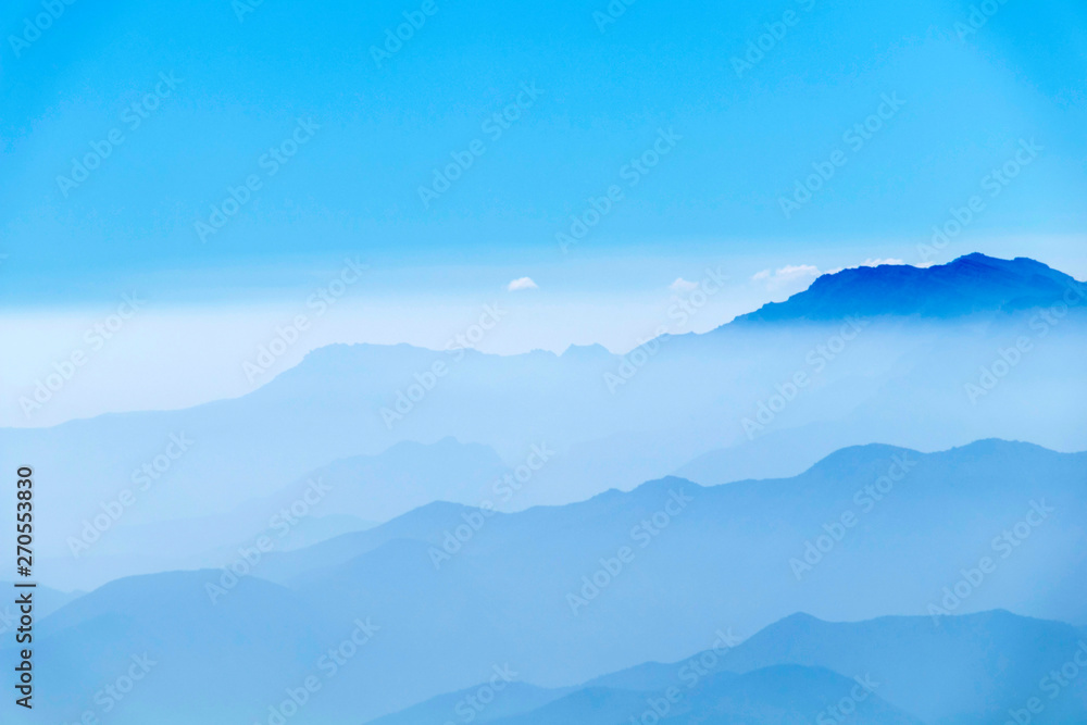 Abstract cascade mountain chains silhouette landscape nackground in a light blue mist sky in morning Andes