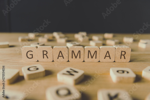 selective focus of word grammar made of cubes surrounded by blocks with letters on wooden surface isolated on black photo