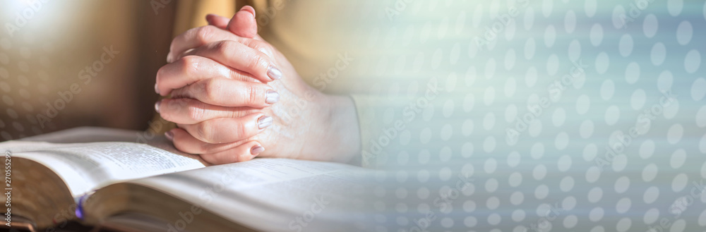 Woman praying with her hands over the bible, hard light; panoramic banner - obrazy, fototapety, plakaty 