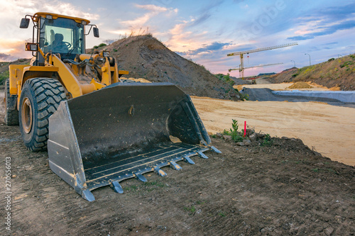 Excavator in a construction site with a crane in the background