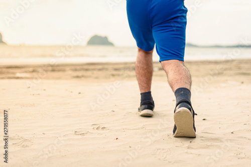 Man runner legs running close up on shoe, Men jogging on the beach