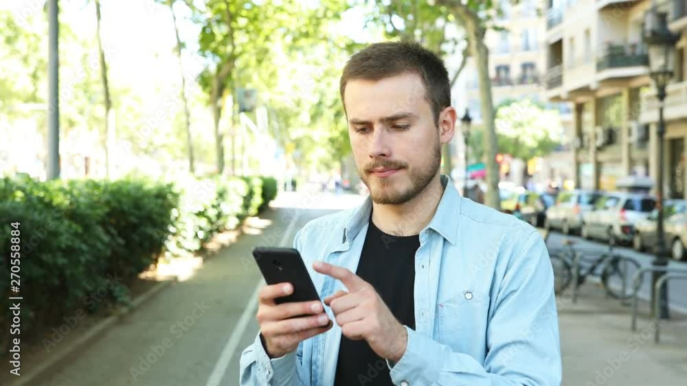 Dissatisfied man uses smart phone in the street and after some time looks at camera with thumb down Dissatisfied man uses smart phone in the street and after some time looks at camera with thumb down