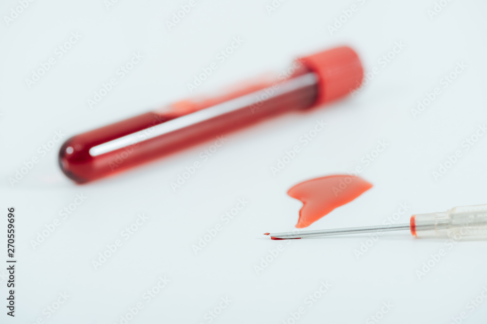 test tube with blood and syringe on white surface test tube with blood and syringe on white surface