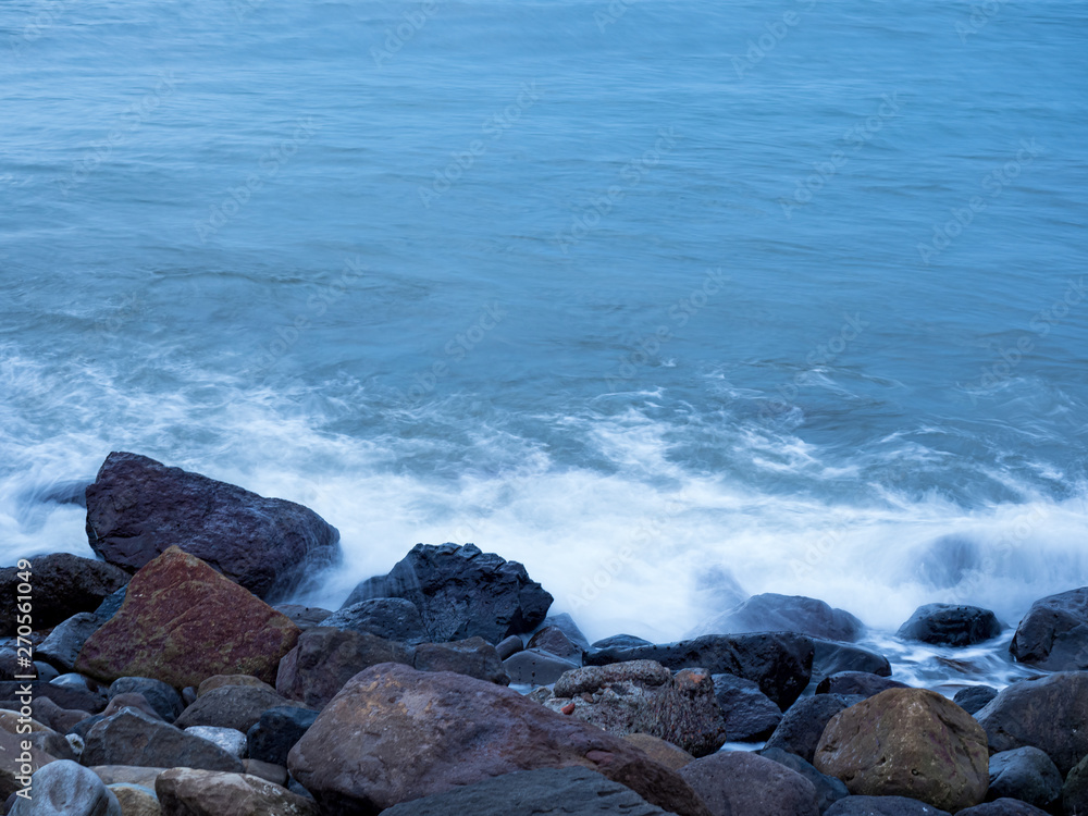 beautiful silky smooth water waves and rocks on the sea shore