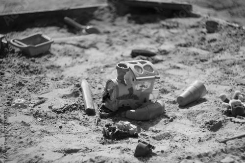 Black and white photo in the sandbox at palyground and playing with toy truck. photo