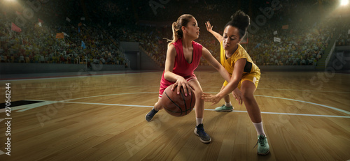 Female basketball players fight for the ball. Basketball players on big professional arena during the game