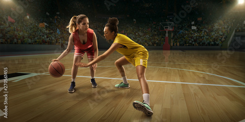 Female basketball players fight for the ball. Basketball players on big professional arena during the game © Alex