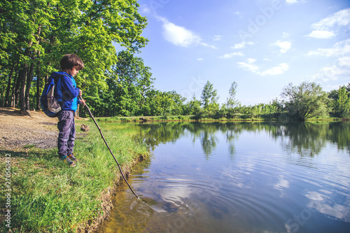 Child play fishing near lake. 