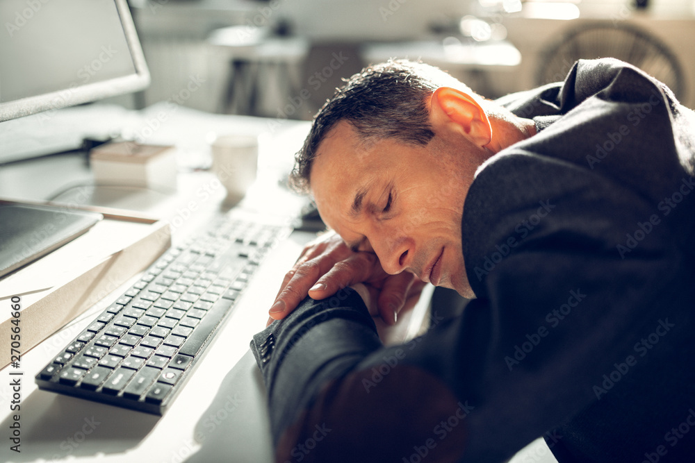 Businessman falling asleep on working table feeling too tired Businessman falling asleep on working table feeling too tired