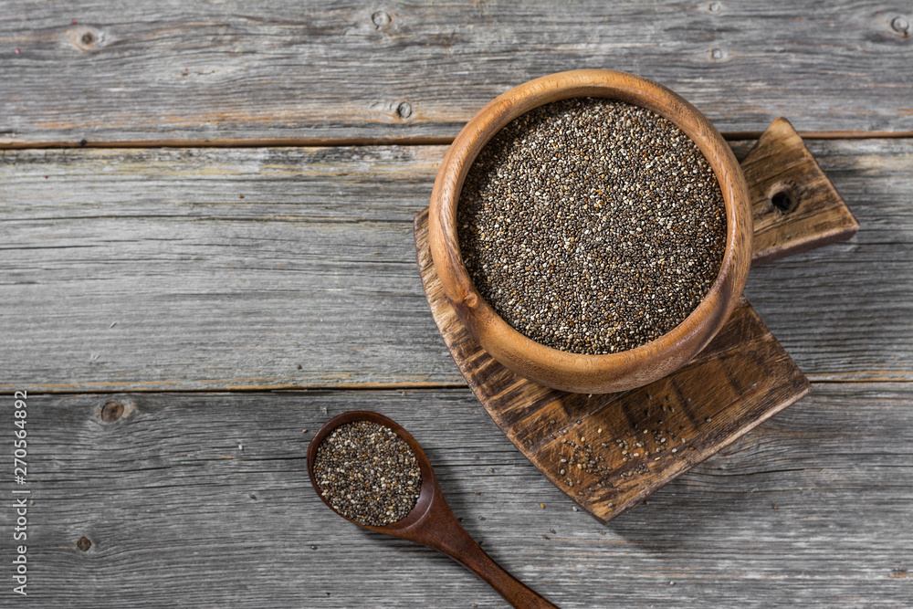 Chia seeds in a wooden bowl on a gray wooden table. Healthy diet. Rustic style Chia seeds in a wooden bowl on a gray wooden table. Healthy diet. Rustic style