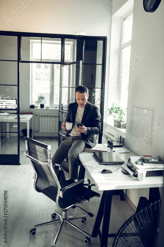 Businessman checking messages on phone while having coffee break