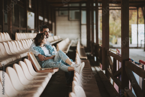 Thoughtful man and woman sitting together on empty sports tribune photo