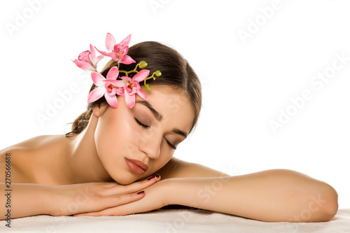 Young woman with makeup posing with orchids on white background