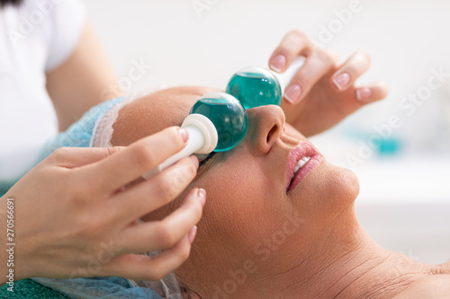 Woman in beauty salon during treatment with a cold glass balls