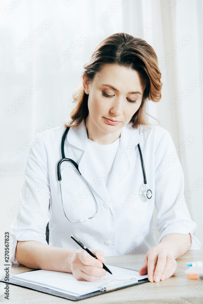 doctor in white coat writing on clipboard in clinic doctor in white coat writing on clipboard in clinic