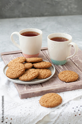 A tasty snack: two cups of tea and a plate of cookies.