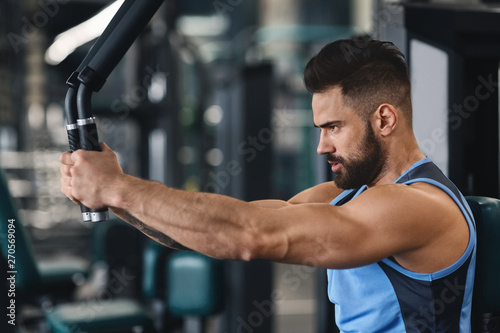 Focused athlete exercising on training machine at gym © Prostock-studio