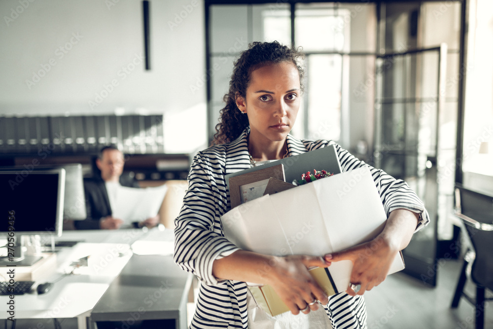 © Viacheslav Yakobchuk - Dark-eyed trainee taking her box with staff after leaving the office