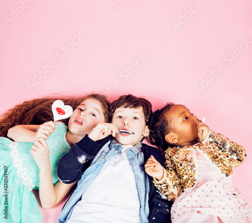 lifestyle people concept: diverse nation children playing together, caucasian boy with african little girl holding candy happy smiling close up