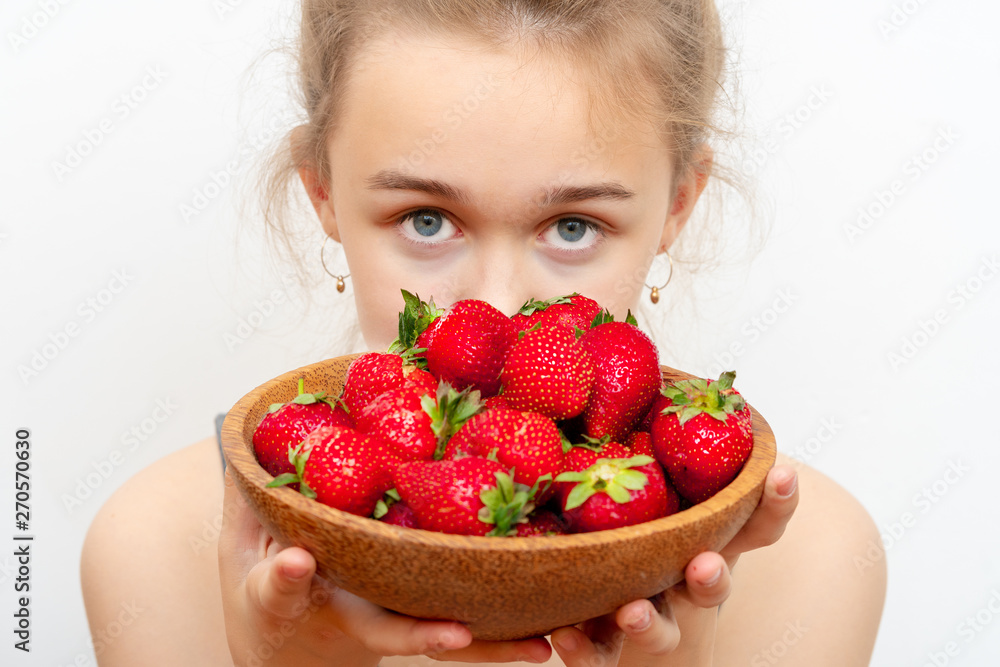 Wooden plate with strawberries in girl hand on light background, organic food concept Wooden plate with strawberries in girl hand on light background, organic food concept