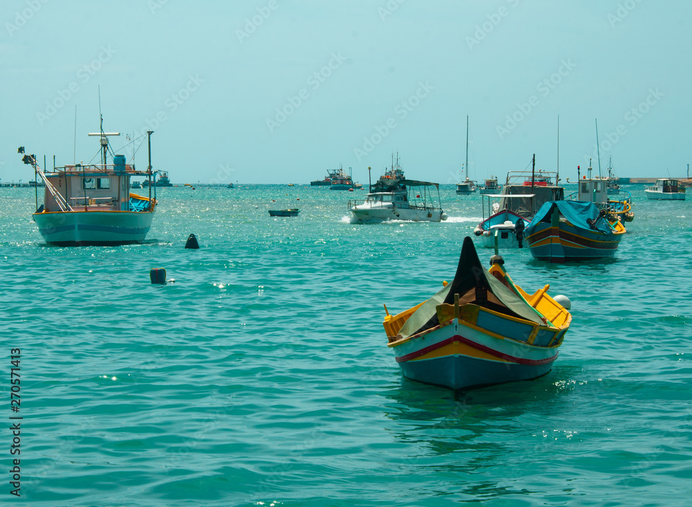Fototapeta premium Colorful poats in aqua blue water. Marsaxlokk malta
