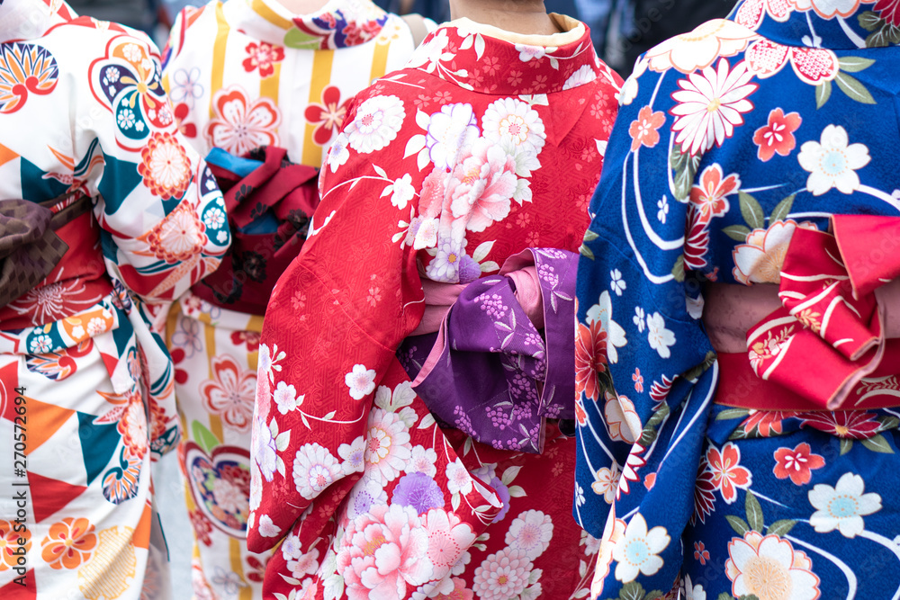 Fototapeta premium Young girl wearing Japanese kimono standing in front of Sensoji Temple in Tokyo, Japan. Kimono is a Japanese traditional garment. The word