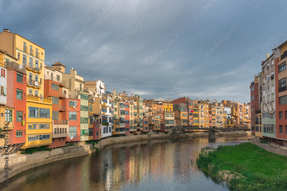 Colorful yellow and orange houses reflected in water in river Onyar. Girona, Catalonia, Spain.