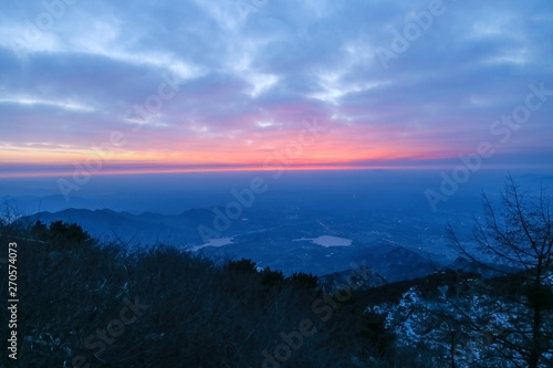 Sunrise view of mount tai. The direction of the mountains.The morning glow of sunrise.Clouds surge, colorful clouds at sunrise.The sunrise on the horizon.Overlooking the city and the lake
