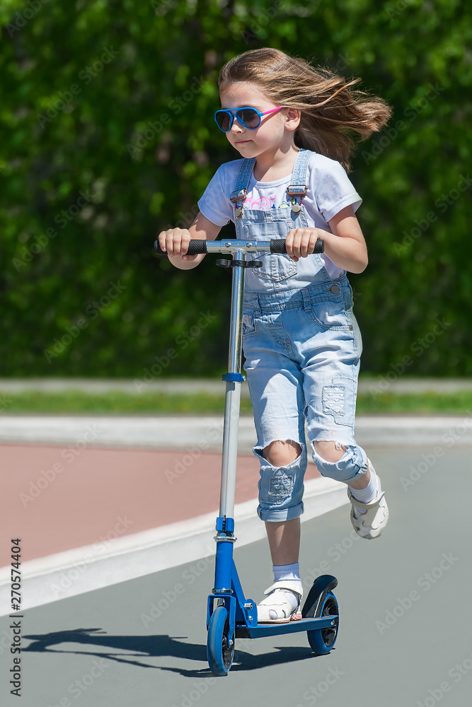 Child riding scooter. Kid on colorful kick board. Active outdoor fun for  kids. Summer sports for preschool children. Little happy girl in spring  park. The concept of a healthy lifestyle foto de