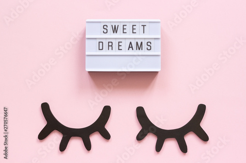 Lightbox text Sweet dreams and decorative wooden black eyelashes, closed eyes on pink paper background. Concept Good night Greeting card Top view Creative flat lay