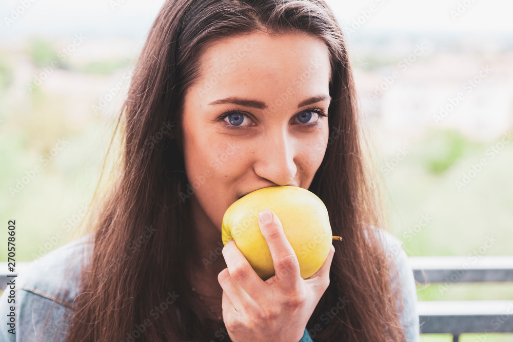 portrait of millennial young female adult eating a green apple