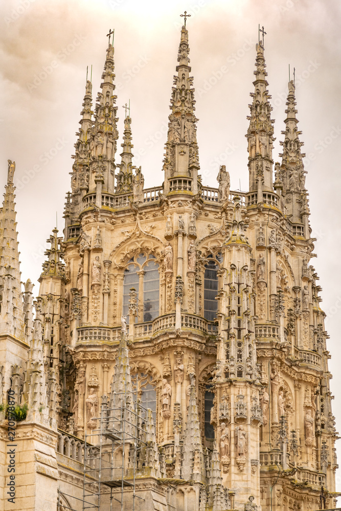 Detail of the lantern of the cathedral of Burgos. Gothic architecture very ornate with pinnacles, sculptures and gargoyles, with a cloudy sky.