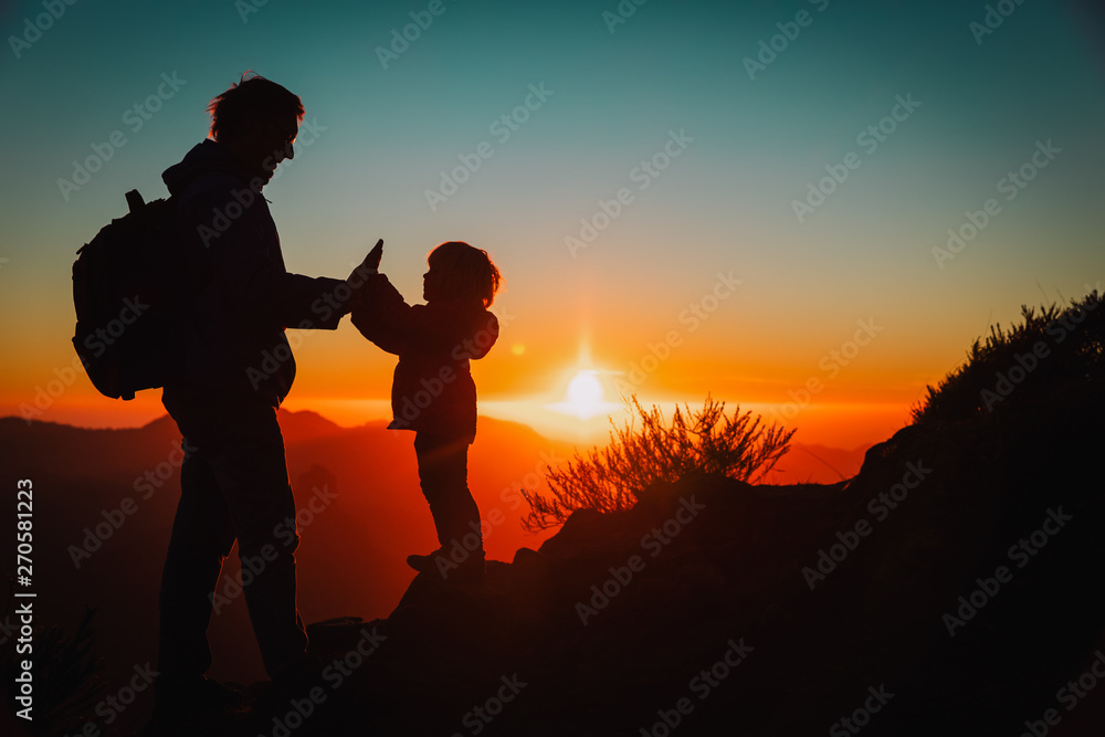 father and little daughter travel in mountains at sunset