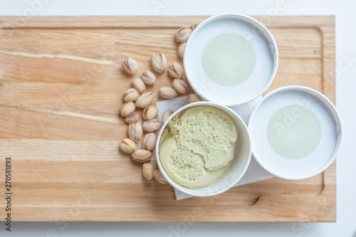 Three cup of pistchio ice cream on kitchen table background with pistachio