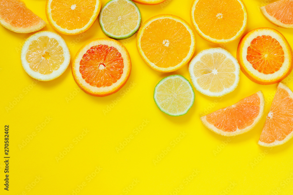 Citrus slices pattern on yellow background from above. Top view of orange, grapefruit, lime and lemon fruit slices on yellow background. Fruit summer cocktail pattern design