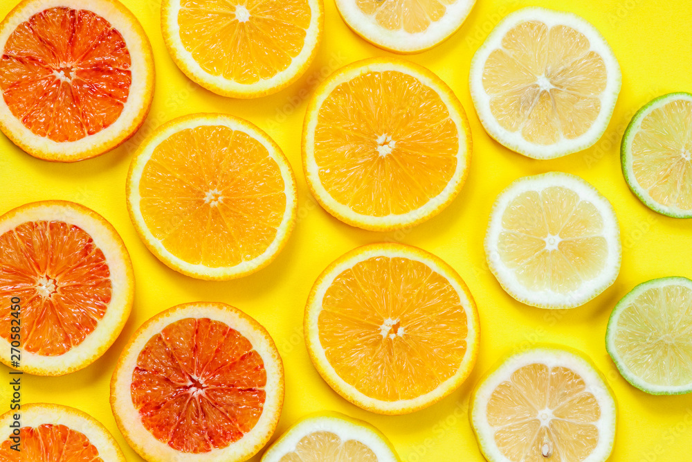 Citrus slices pattern on yellow background from above. Top view of orange, grapefruit, lime and lemon fruit slices on yellow background. Fruit summer cocktail pattern design Citrus slices pattern on yellow background from above. Top view of orange, grapefruit, lime and lemon fruit slices on yellow background. Fruit summer cocktail pattern design