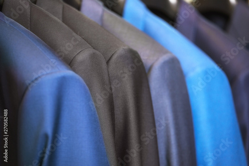 close up luxurious style gentlemen suit row, hanging in a closet .